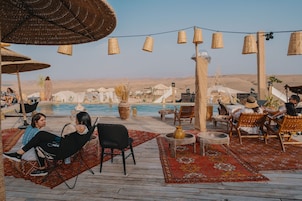 Una piscina al aire libre, sombrillas, sillones reclinables de piscina