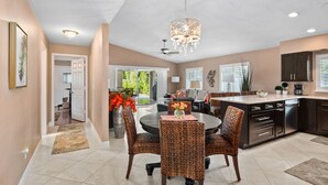 A spacious kitchen with dark cabinetry, a round dining table, wicker chairs, and a chandelier. - Amazing private pool-spa home just blocks from the beach.  (Naples)