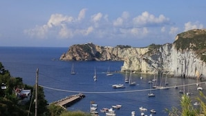 A coastal view with boats anchored near cliffs and a dock. - Domes, flowers and a small, cool pool (Le Forna)