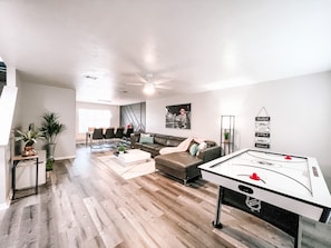 A spacious living room with a pool table, a sofa, and a dining area with chairs.