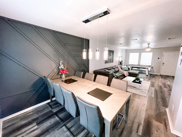 A modern living space with a dining area, a sofa, and a pool table.