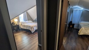Une chambre avec un plafond en pente, un lit, une table de chevet et une lampe.