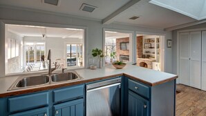 Een moderne keuken met blauwe kasten, een roestvrijstalen vaatwasser en een groot eiland met een spoelbak.