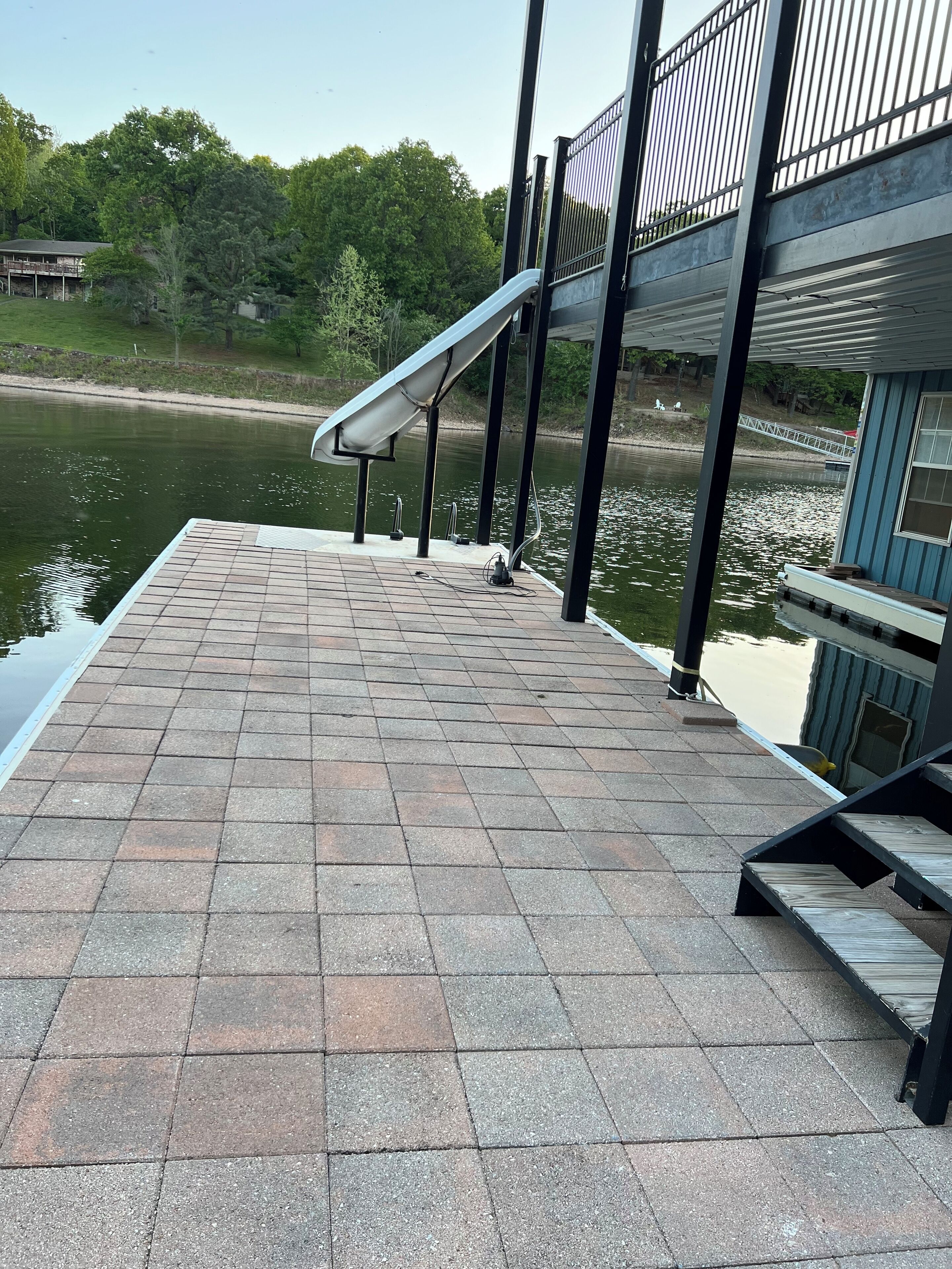A dock with a metal railing, a solar panel, and a water body in the background.