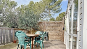 A wooden deck with a table and chairs, surrounded by a wooden fence and trees. - Mobile home 32 m2. Sleeps 4. In a secure residence (Le Castellet)