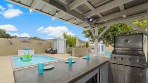 Ein Außenbereich mit Küche, Grill, Pool und Barbereich.