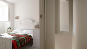 Ein Schlafzimmer mit einem Bett, einem Nachttisch, einer Lampe und einem Fenster.