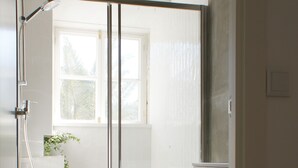 Ein modernes Badezimmer mit Duschkabine, Toilette und kleinem Fenster.