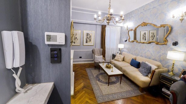 Hotellihuone, jossa on marmoripintainen työpöytä, sohva, kattokruunu ja suuri peili.