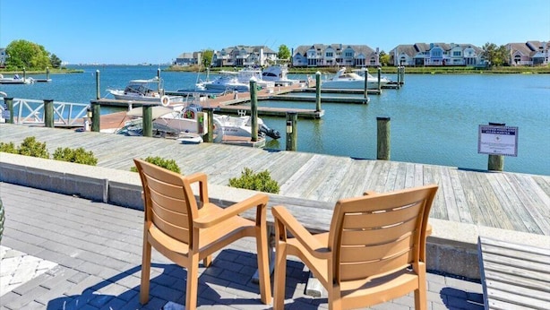 A waterfront dock with wooden chairs and a sign indicating a marina.