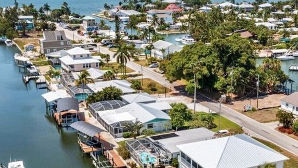 Zona residencial costera con casas, un puerto deportivo y una piscina.