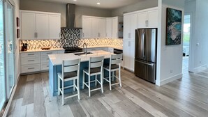 Una cocina moderna con armarios blancos, un refrigerador de acero inoxidable y un salpicadero de azulejos.