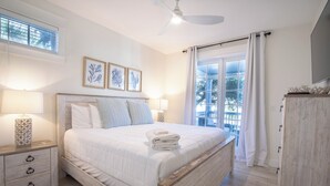 Quarto com cama grande, abajures, ventilador de teto e vista para o exterior através de uma janela.