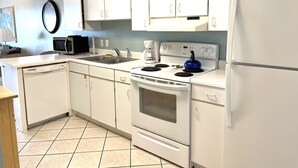 A kitchen with white cabinets, a microwave, a sink, a stove, and a refrigerator. - Surf Side Shores 2405  2 bd 2 ba  gulf-front  (Gulf Shores)