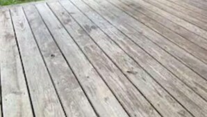 En gyngestol i træ på en veranda med en græsplæne i baggrunden.
