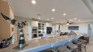 Uma cozinha moderna com armários brancos, bancada de granito e um espaço bar com banquetas.