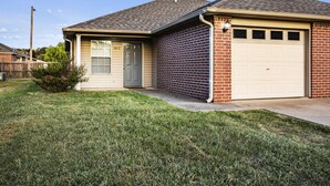 A single-story house with a garage, a front door, and a small front yard. - Cheerful 2 Bedrooms 2 Full Bathrooms Duplex (Fort Smith)