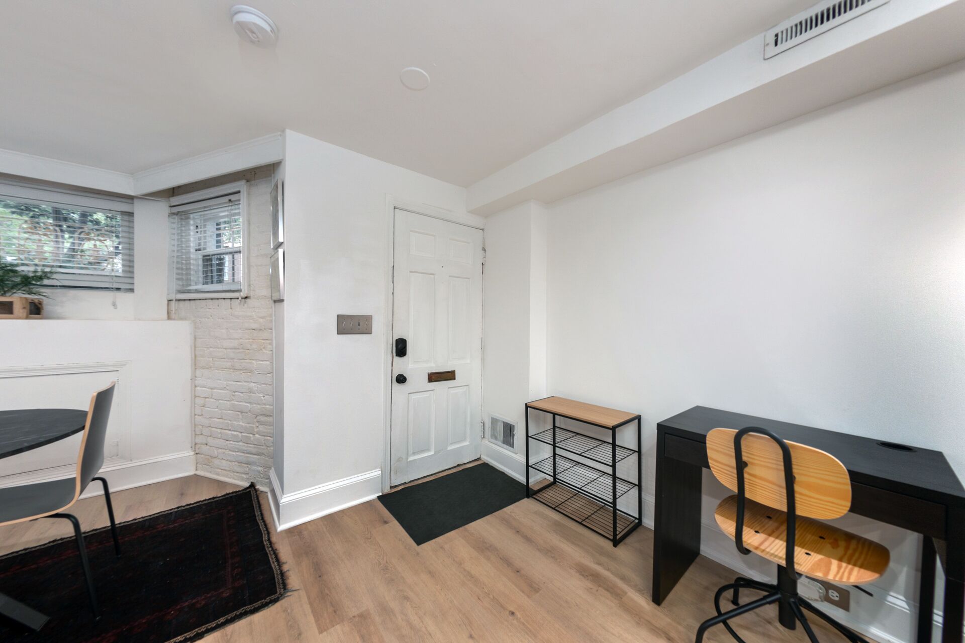 Une chambre moderne avec un plancher en bois, un bureau avec une chaise, une petite table et une porte avec une boîte aux lettres.