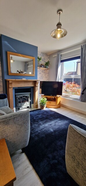 A living room with a fireplace, a television, and a large window with a view of the outside.