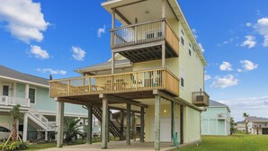 A multi-story building with a balcony on the second floor and a covered area on the first floor. - Sunflower Surf by Ryson Vacation Rentals (Galveston)