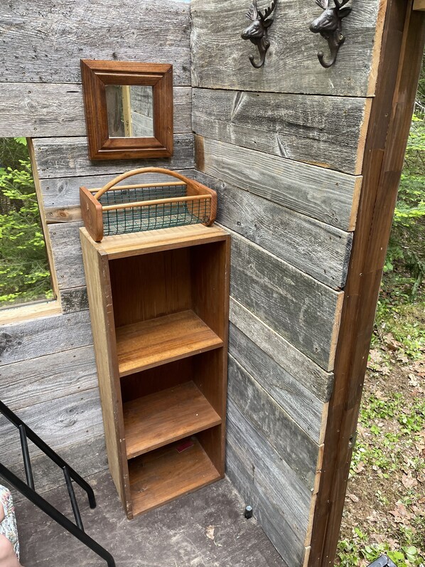 Un espace extérieur aménagé avec des meubles en bois, comprenant une table avec un gril en métal, un banc en bois et un miroir fixé au mur.
