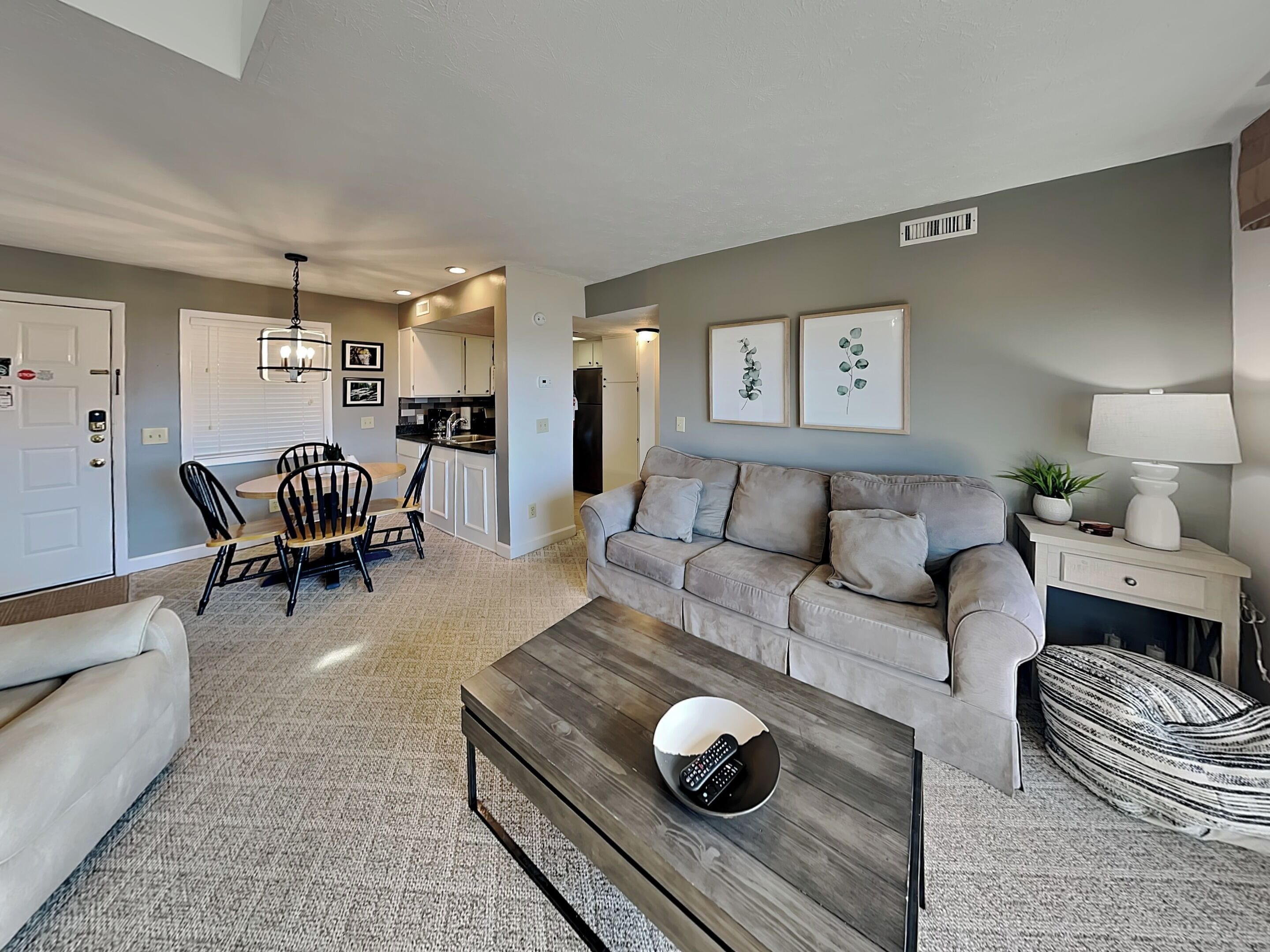 A living room with a beige sofa, a wooden coffee table, and a dining area with a table and chairs.