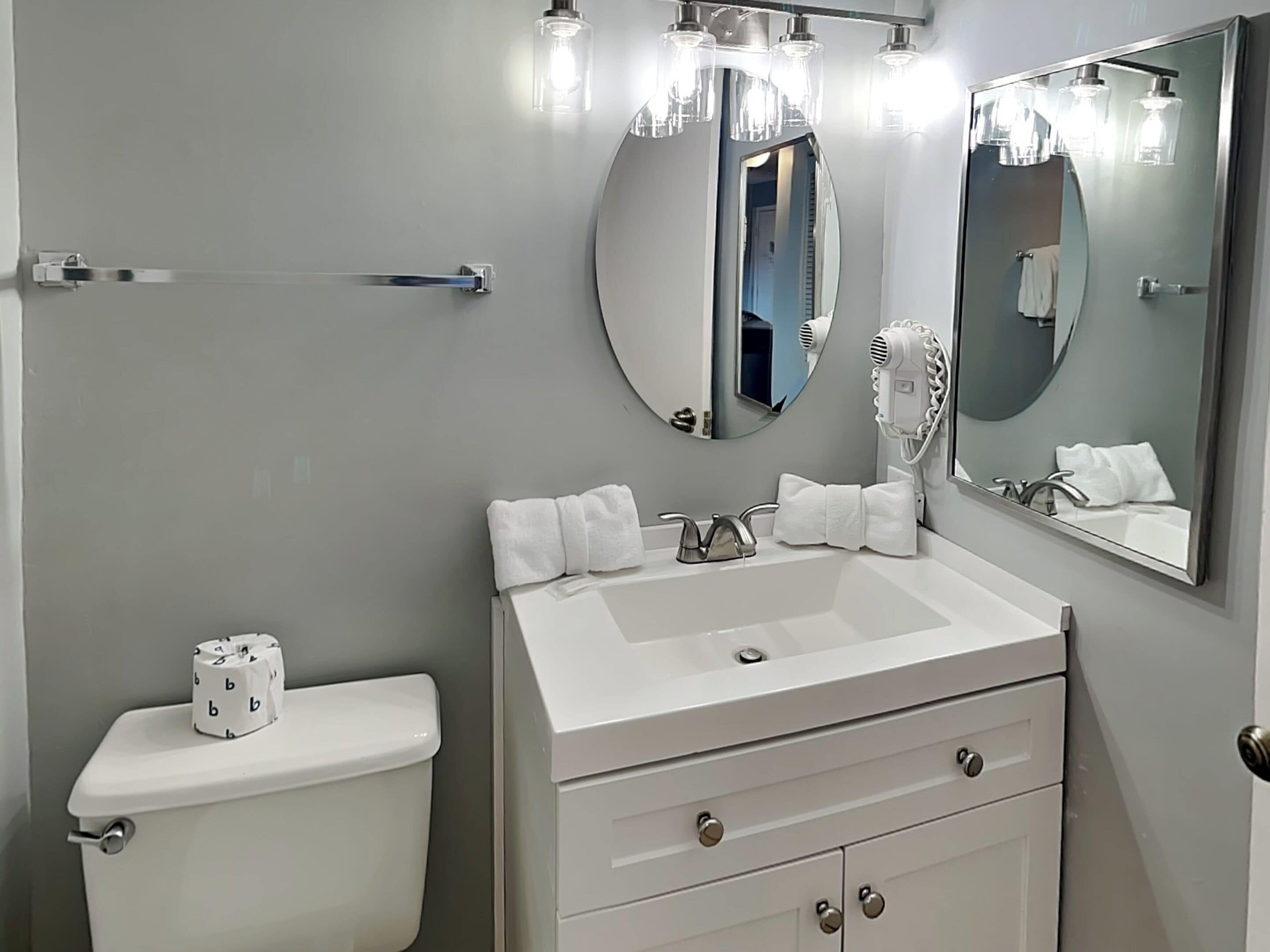 A bathroom with a toilet, a sink with a mirror, and a towel rack.
