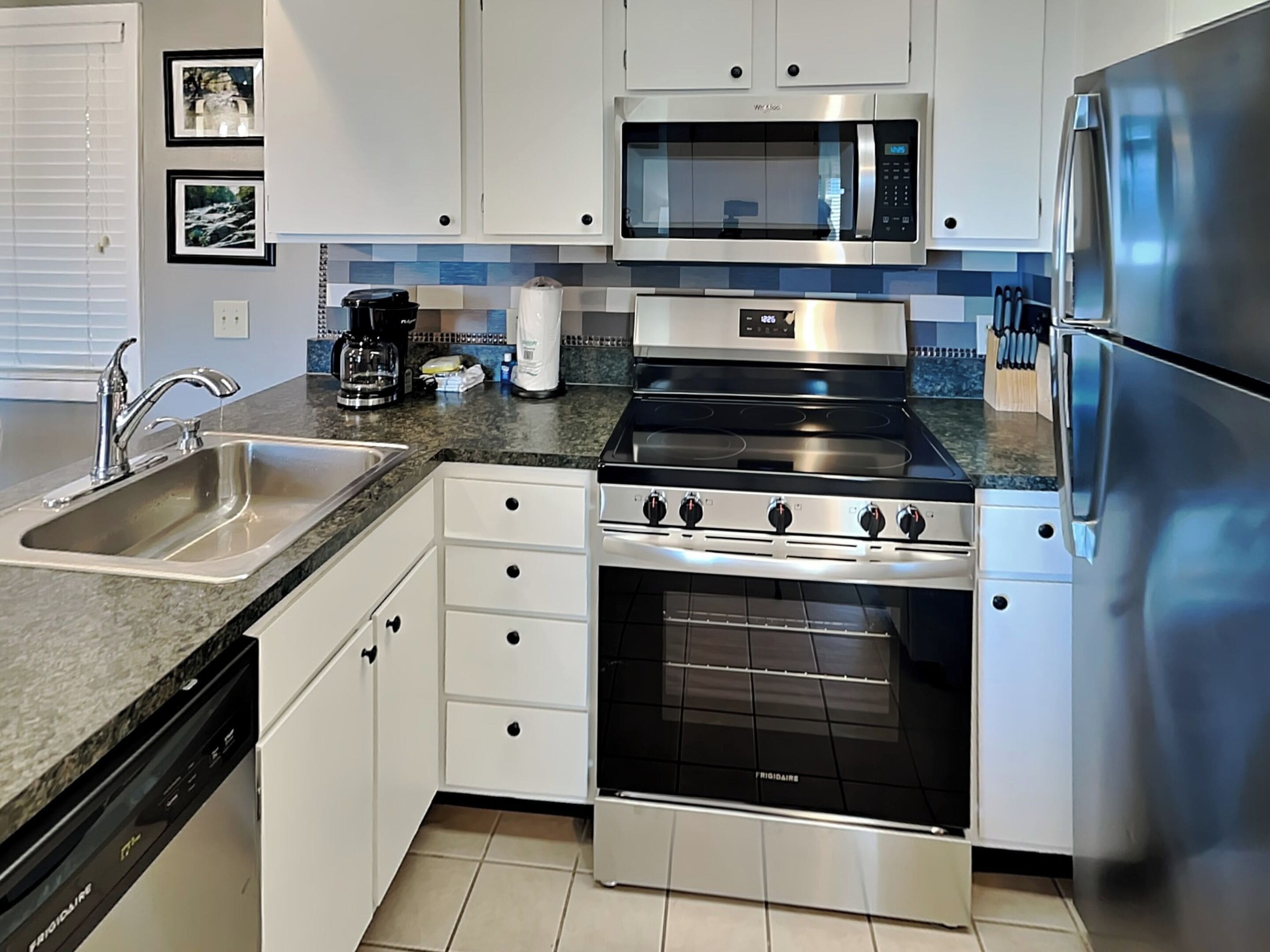 Una cocina moderna con electrodomésticos de acero inoxidable, un lavamanos doble y armarios blancos.
