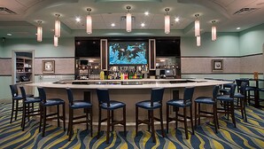 A bar area with a counter, stools, and a large screen displaying an underwater scene.