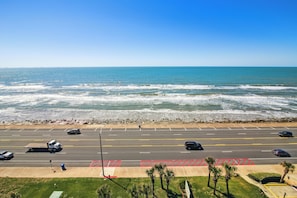 A coastal road with a parking lot, beach, and ocean view. - Pelican View by Ryson Vacation Rentals (Galveston)