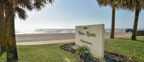 Señal de Ocean Grove con vista a la playa y palmeras.
