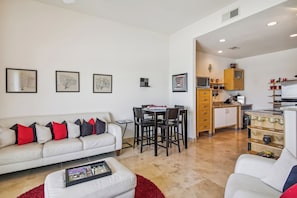 A modern living room with a white sofa, red and black cushions, a coffee table, and framed artwork on the wall. - Pelican View by Ryson Vacation Rentals (Galveston)