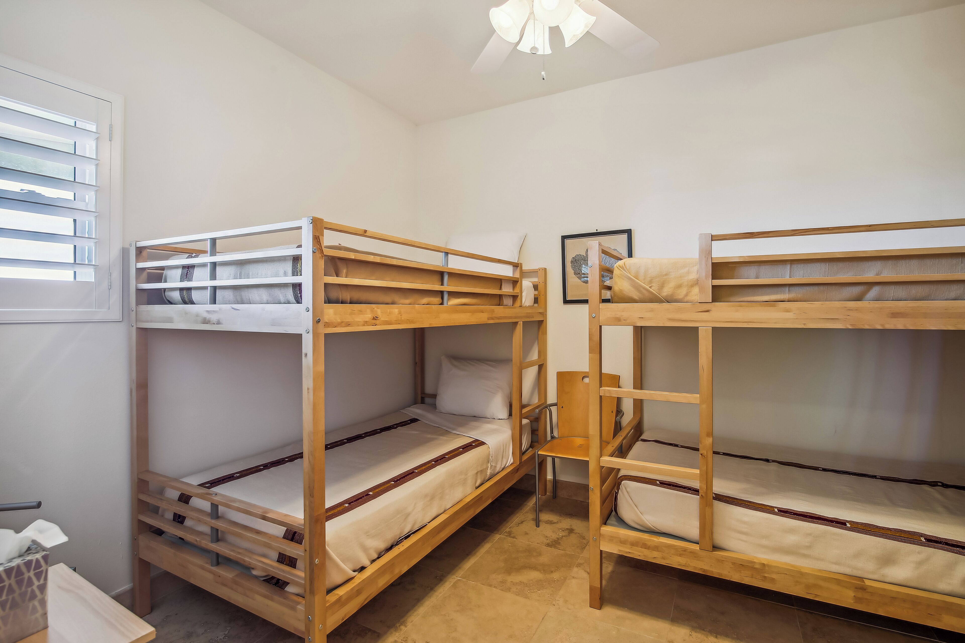 A room with two bunk beds, a small table, and a chair.