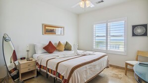 A neatly arranged bedroom with a bed, bedside table, and a chair. - Pelican View by Ryson Vacation Rentals (Galveston)
