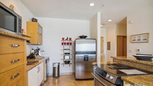 A modern kitchen with wooden cabinets, stainless steel appliances, and granite countertops. - Pelican View by Ryson Vacation Rentals (Galveston)