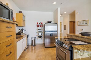 A modern kitchen with wooden cabinets, stainless steel appliances, and granite countertops. - Pelican View by Ryson Vacation Rentals (Galveston)