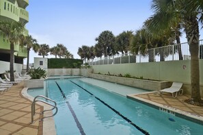 A swimming pool with clear lane dividers, surrounded by palm trees and lounge chairs. - Pelican View by Ryson Vacation Rentals (Galveston)