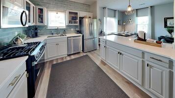 Una cocina moderna con armarios blancos, un refrigerador de acero inoxidable y un horno empotrado.