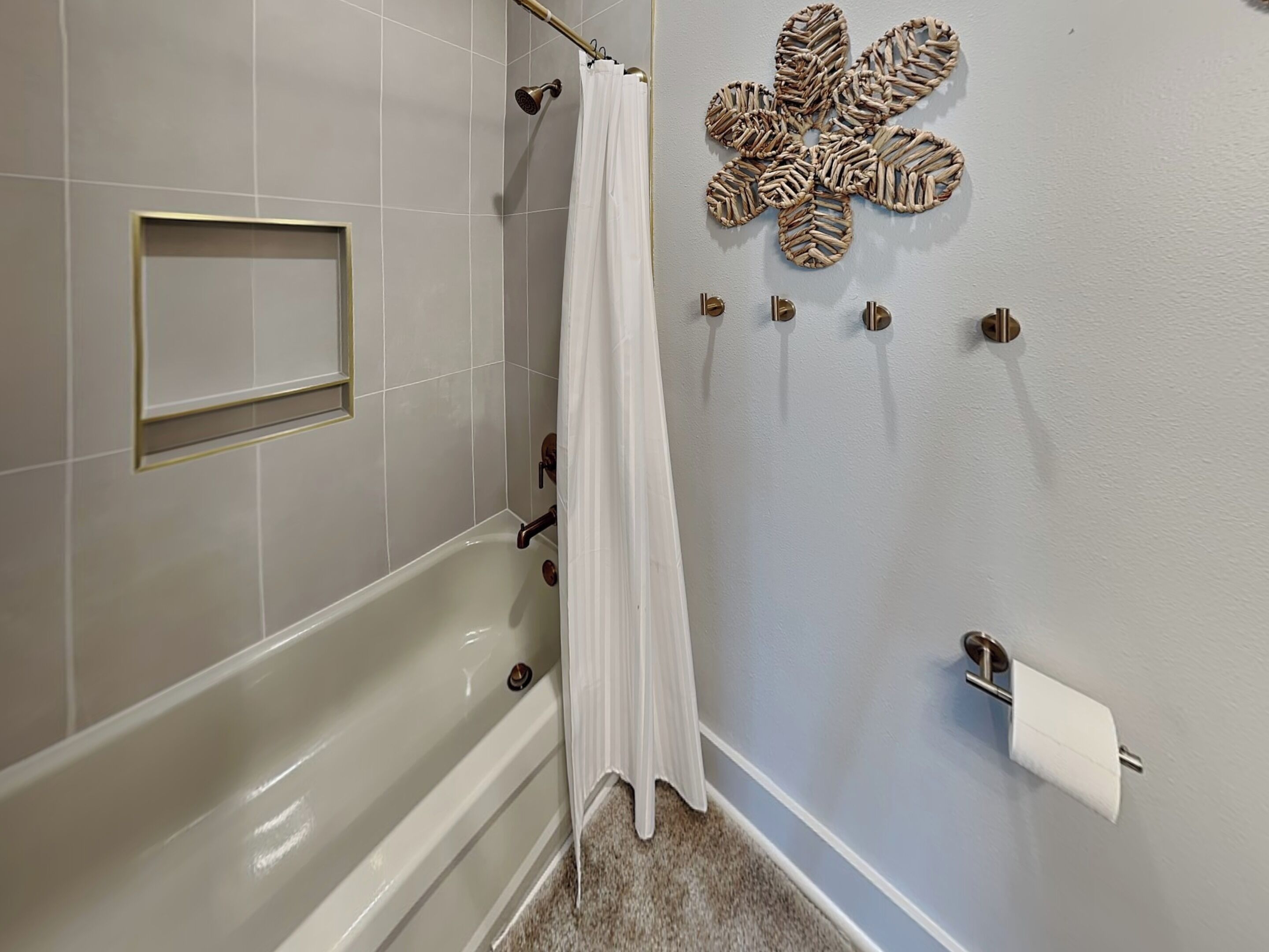 Un baño con bañera, cortina de ducha, toallero y soporte para papel higiénico.