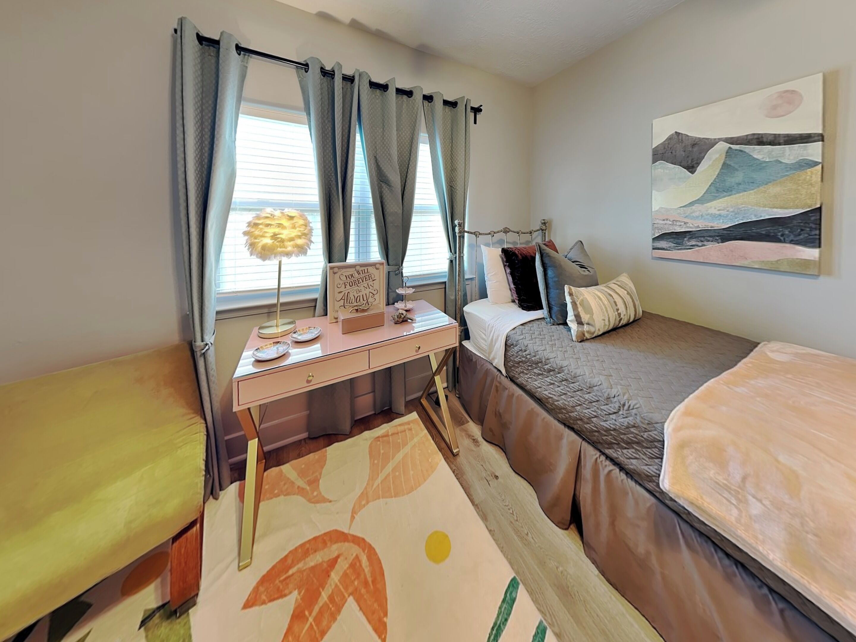 A bedroom with a bed, a desk, a chair, a window with curtains, and a painting on the wall.