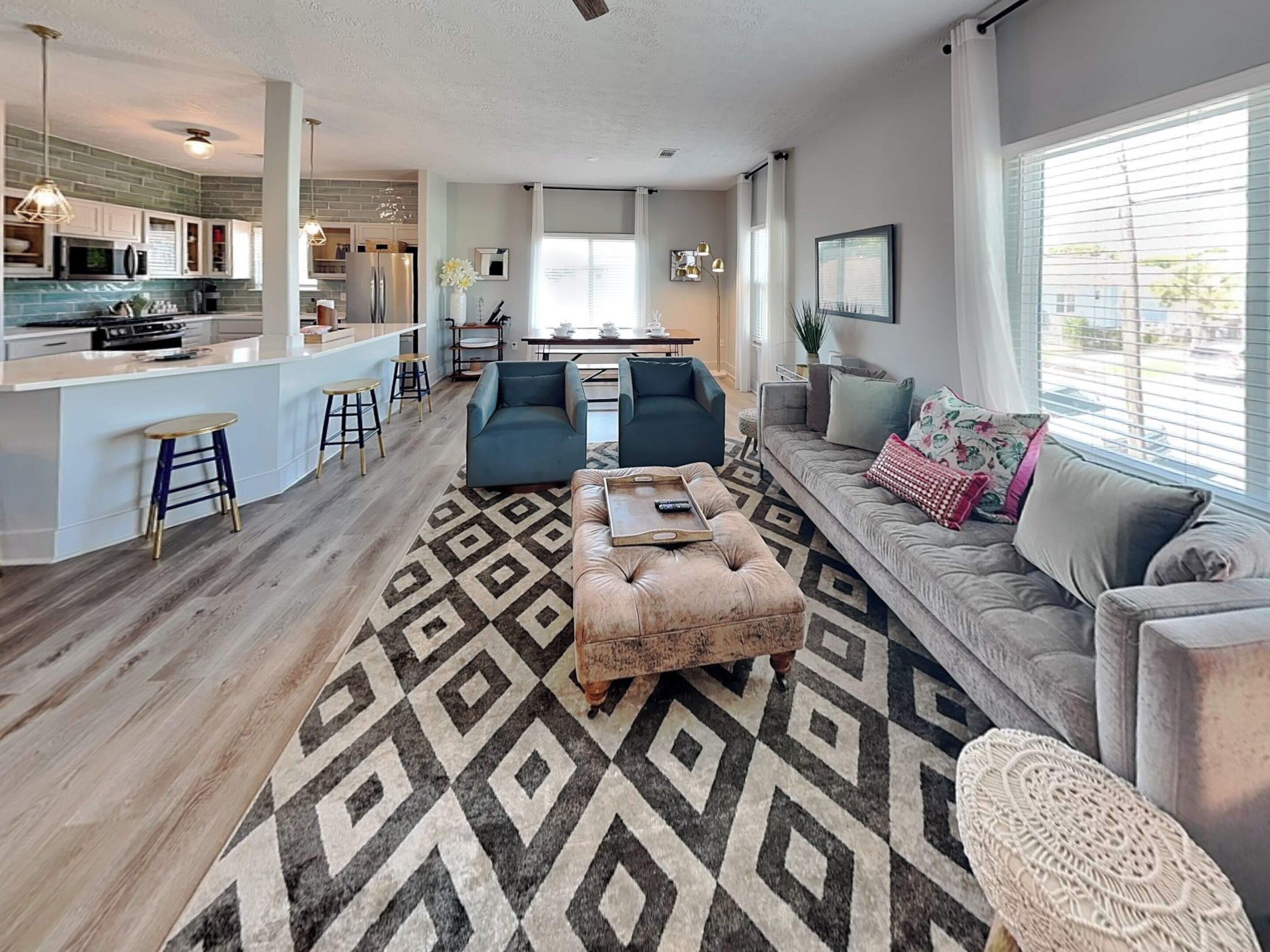 Una sala de estar moderna con sofá, reposapiés y mesa de centro, un área de cocina con barra y un espacio para comer.