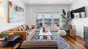 A modern living room with a sofa, a coffee table, and a TV. - Waterfront, Sunset Views! Historic Dwtn-King Bed-Luxury with Free Parking!  (Wilmington)