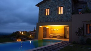 A stone house with a swimming pool, a patio, and a well-lit interior. - Wonderful Private Villa With Pool in Riparbella (Riparbella)