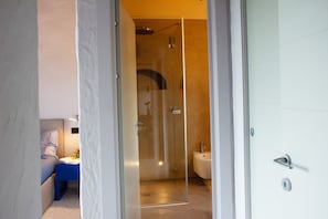 A modern bathroom with a glass shower enclosure, a toilet, and a bed with a blue headboard. - Wonderful Private Villa With Pool in Riparbella (Riparbella)
