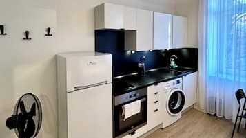 Cocina compacta equipada con refrigerador, horno, lavadora y pileta.