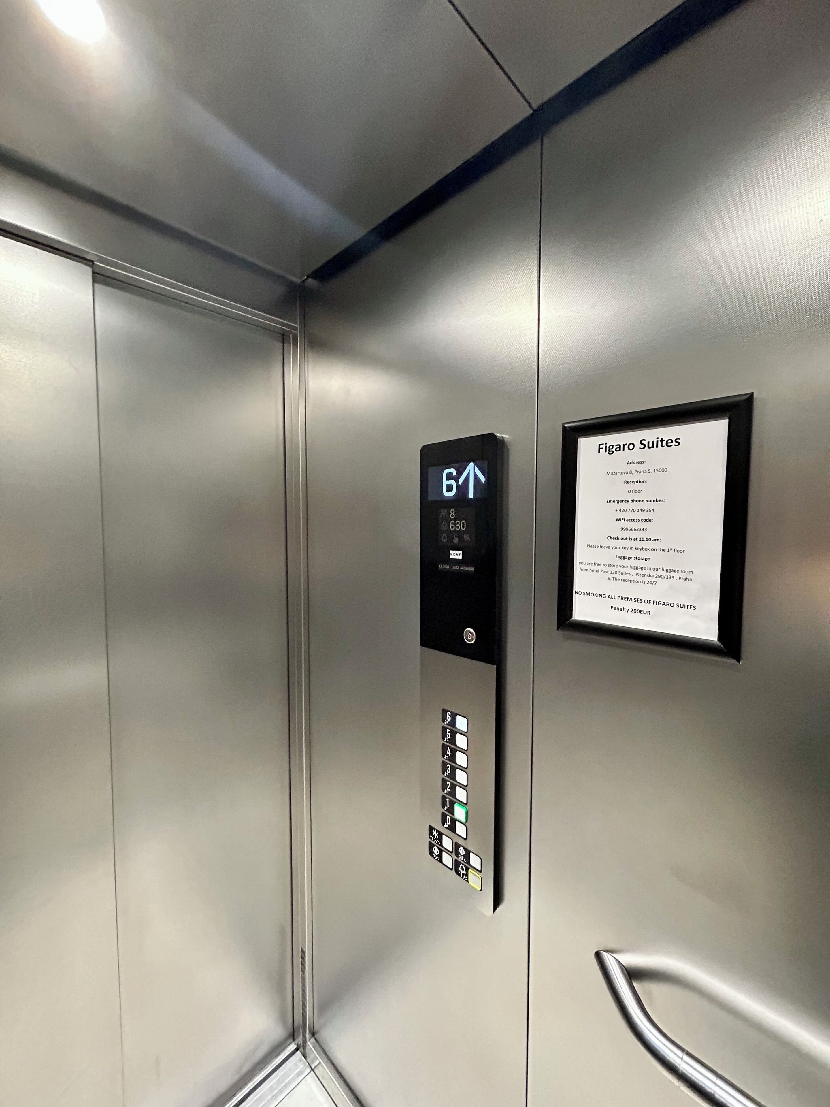 An elevator interior with a digital display indicating the 6th floor, a keypad, and a sign for Figaro Suites with reception details.