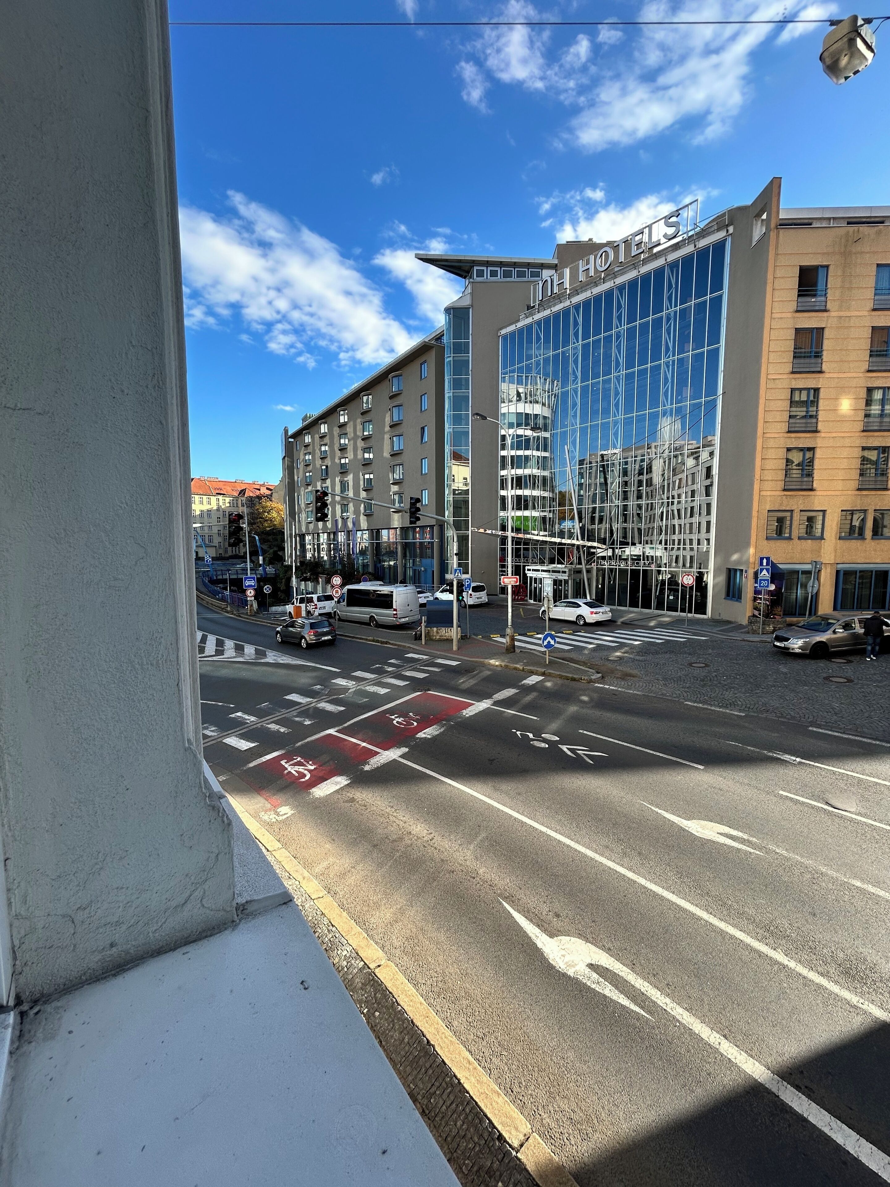 A modern hotel with a glass facade, a prominent 'HOTEL' sign, and a pedestrian crossing.