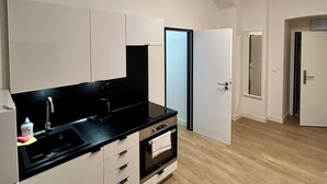 Una cocina moderna con armarios blancos, encimera negra y horno integrado.
