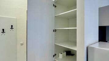 Een inpandige kast met open deuren, waarin planken en een klein vak zichtbaar zijn.