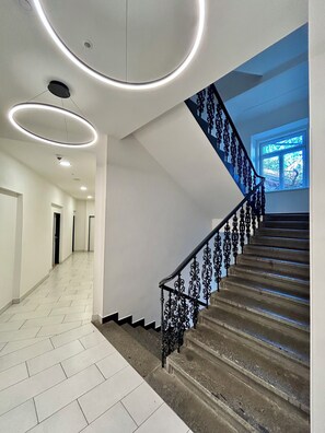 Een modern interieur met een trap, witte muren en een betegelde vloer.